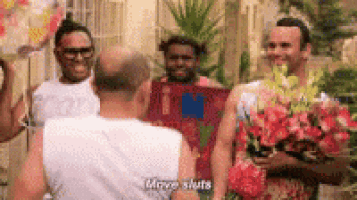a group of men are standing next to each other holding flowers and one of them is saying move shuts