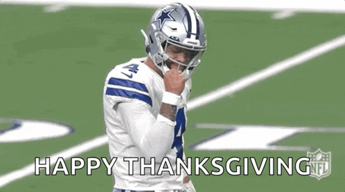 a football player is standing on a field with his fist in the air and says happy thanksgiving .