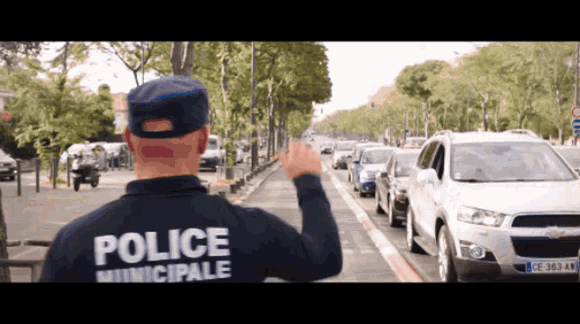 a man wearing a blue jacket that says police municipale waving