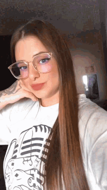 a woman wearing glasses takes a selfie with her hand on her face