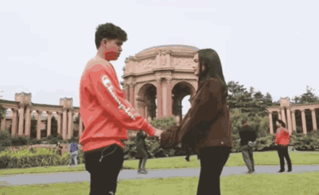 a man wearing a red champion sweatshirt holds a woman 's hand