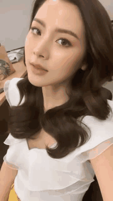 a close up of a woman taking a selfie in a white top .