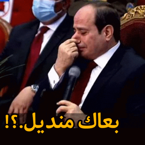 a man in a suit and tie is crying and covering his nose with his hand