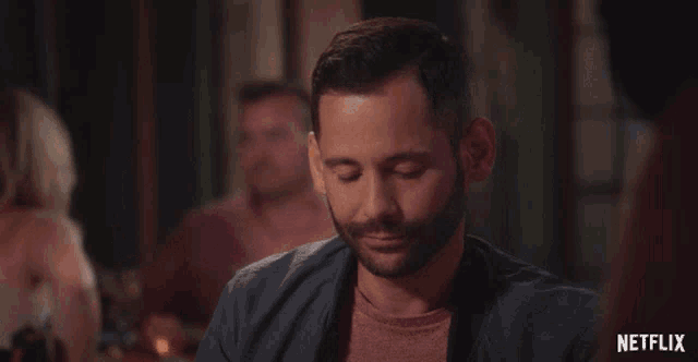 a man sits at a table with his eyes closed and a netflix logo in the corner