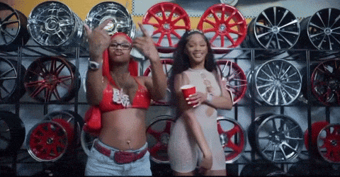 two women are dancing in front of a wall of wheels