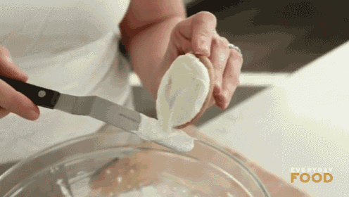 a woman is using a spatula to spread frosting on a banana .