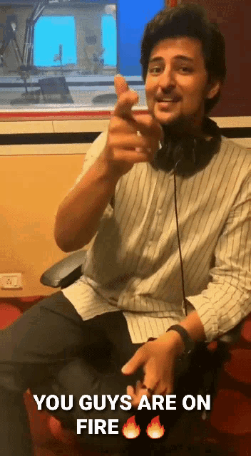 a man wearing headphones is pointing at the camera with the words " you guys are on fire " above him