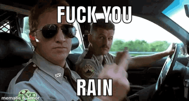 two police officers are sitting in a car and one of them is pointing at the camera while the other says " fuck you rain "