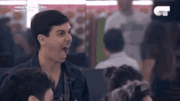 a man is screaming in a crowd of people while sitting at a table .