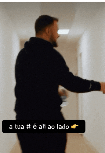 a man in a black hoodie is walking down a hallway