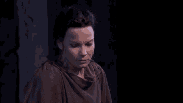 a woman in a dark room with her eyes closed looks down