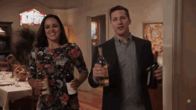 a man and a woman are holding bottles of wine in their hands
