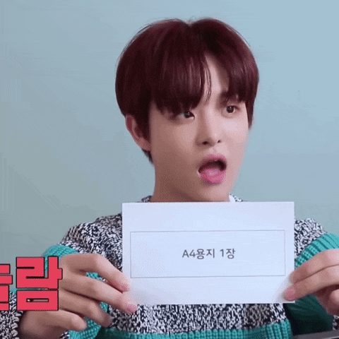 a young man with red hair is holding a piece of paper with a4 on it .