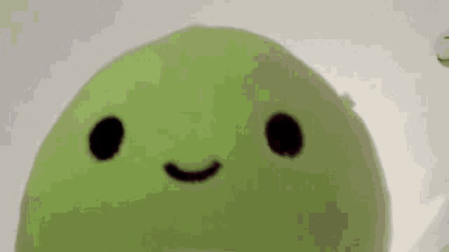 a close up of a green stuffed animal with a black face .