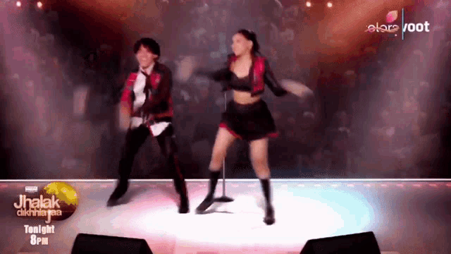 a man and a woman are dancing on a stage in front of a sign that says " tonight 8pm "