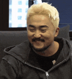 a man with blonde hair and a beard wearing a black jacket with a zipper