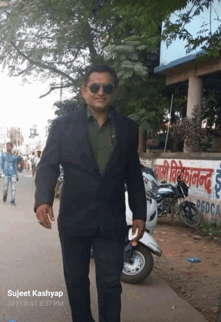 a man in a suit and sunglasses is standing in front of a building that says pgdca on it