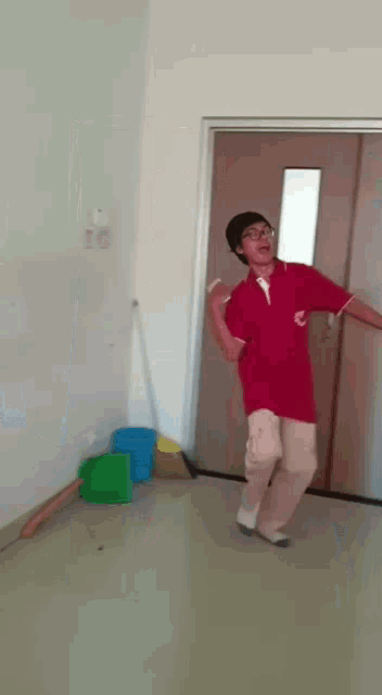 a boy in a red shirt is dancing in a room