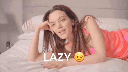 a woman in a pink dress is laying on a bed with the word lazy written above her