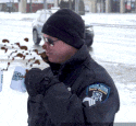 a man in a police uniform is drinking from a mug in the snow