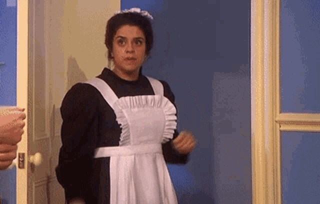 a woman in a maid 's outfit is standing in a doorway