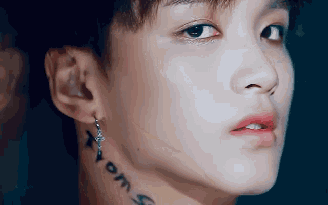 a close up of a man 's face with a tattoo on his neck and earrings .