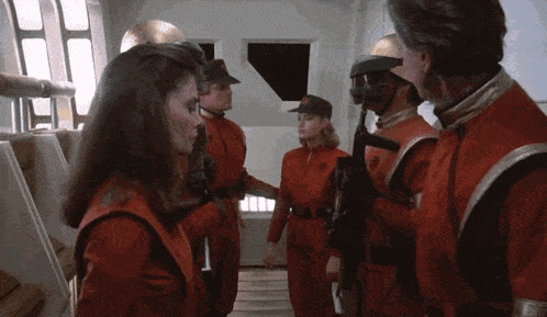a group of people in red jumpsuits are standing next to each other in a room