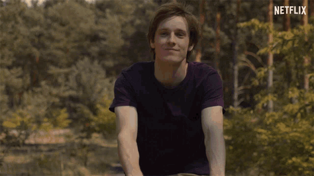 a man in a purple shirt is smiling in front of a netflix sign