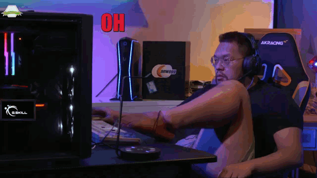 a man wearing headphones sits in front of a g.skill computer