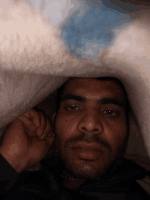 a man with a beard is laying under a white blanket