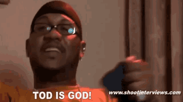 a man with glasses says tod is god while holding a cell phone