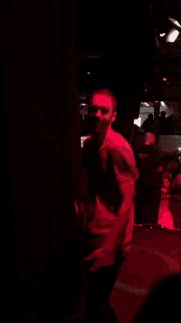 a man is dancing in a dark room with red lights behind him