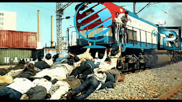 a group of people are laying on the tracks in front of a train that has the letter h on the side