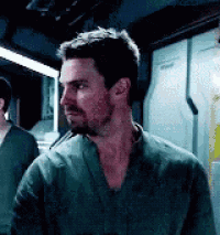 a man with a beard and a green shirt is standing in a room looking at something .