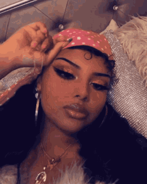 a woman is laying on a bed wearing a pink headband and earrings .