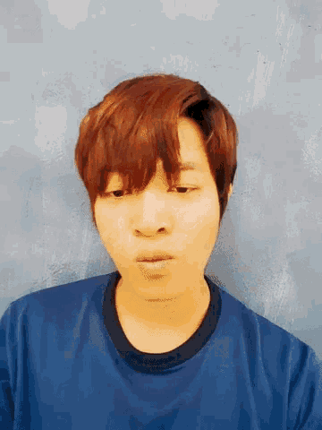 a man in a blue shirt is smiling and making a funny face .