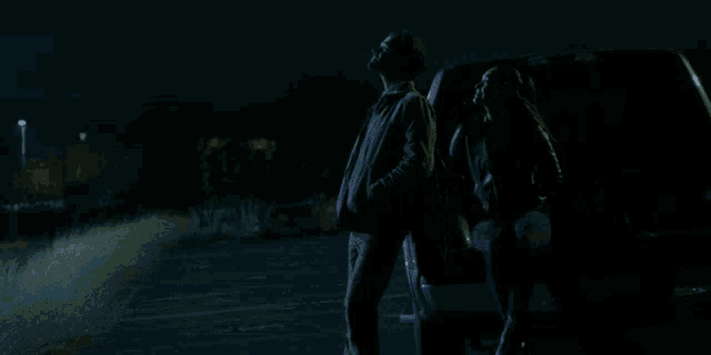 a man and a woman are standing next to each other in the dark