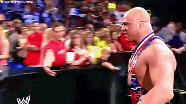 a wrestler wearing a medal around his neck is standing in front of a crowd .