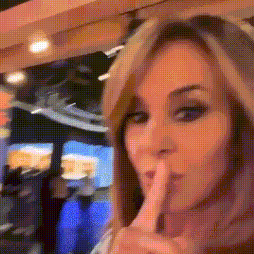 a woman is holding her finger to her mouth and making a shhh sign .