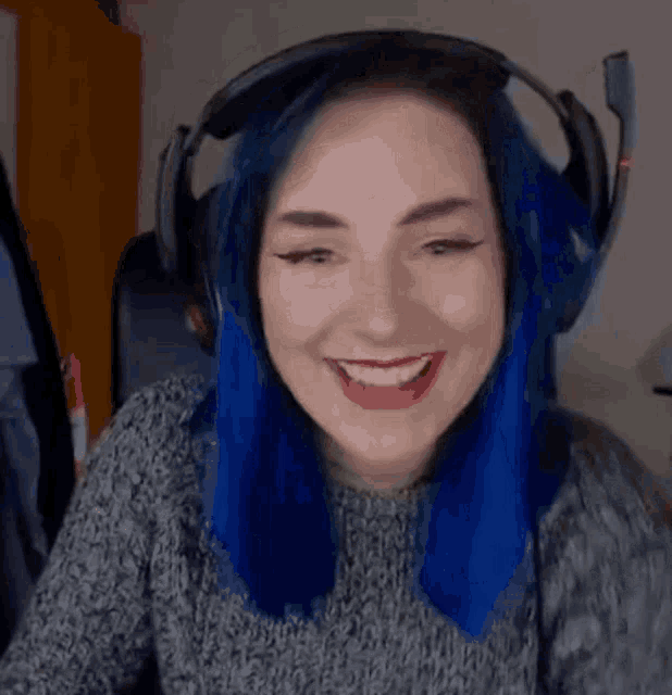 a woman with blue hair wearing headphones is smiling .