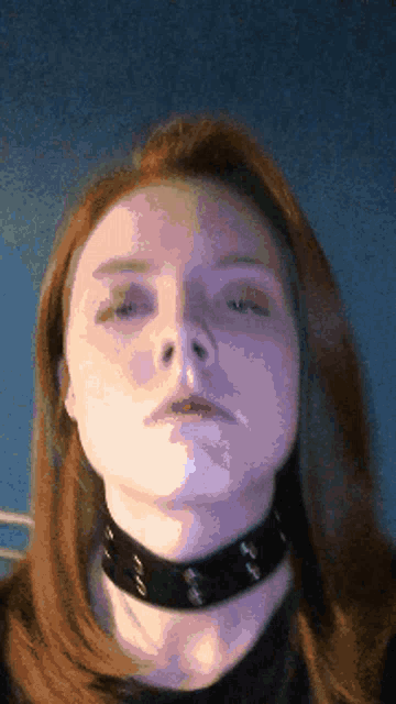 a woman wearing a black choker looks at the camera