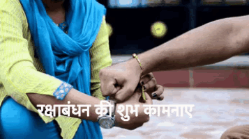 a woman in a blue scarf is holding a man 's hand with a bracelet on his wrist