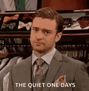 a man in a suit and tie is standing in front of a display of ties and says `` the quiet one days '' .