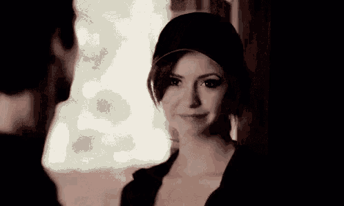 a woman wearing a baseball cap is smiling while looking at a man .
