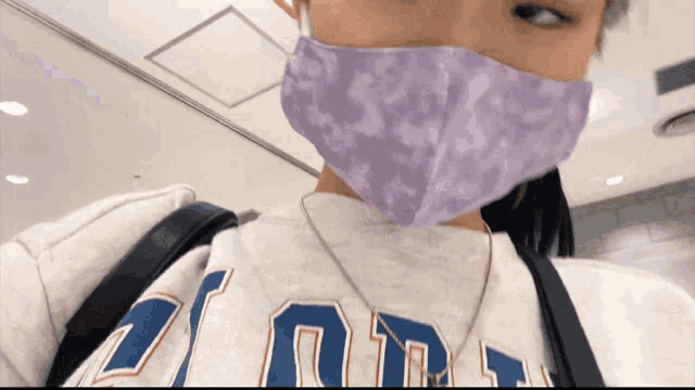 a woman wearing a purple mask and a sweatshirt that says ' zion ' on it
