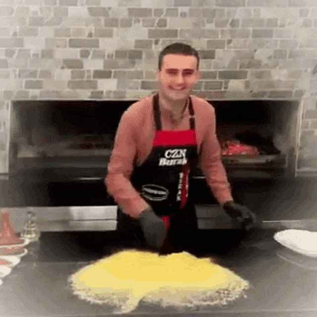 a man wearing an apron that says czn burak is preparing food