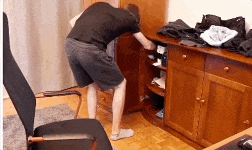 a man in a black shirt is reaching into a drawer