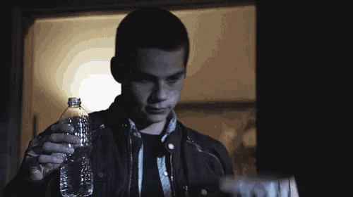 a man is holding a bottle of water and a bowl that says scott