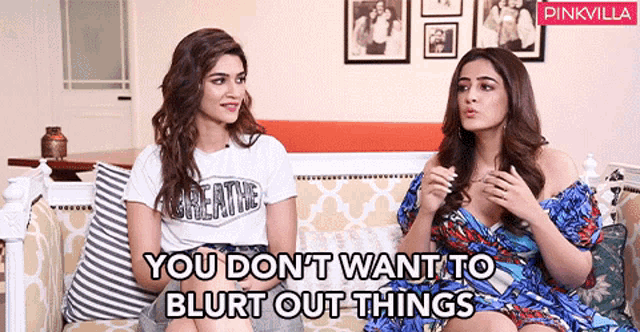 two women are sitting on a couch and one of them is wearing a white shirt that says creative