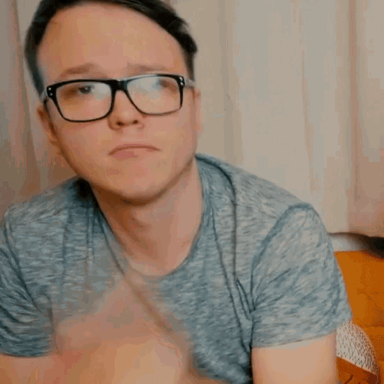 a man wearing glasses making a peace sign
